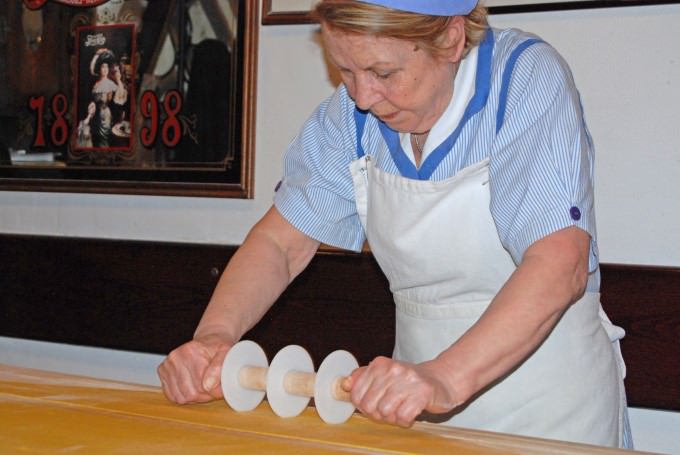Luisa cuts the pasta dough into shapes for tortellini