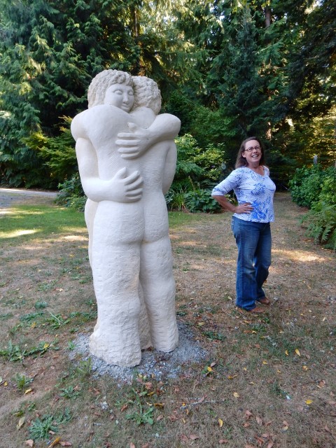 Karla Matzke standing by sculpture “Hug Me Like a Rock”, by Tracy Powell.